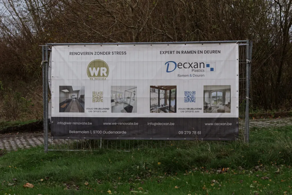 Spandoek van We Renovate aan een werfhek