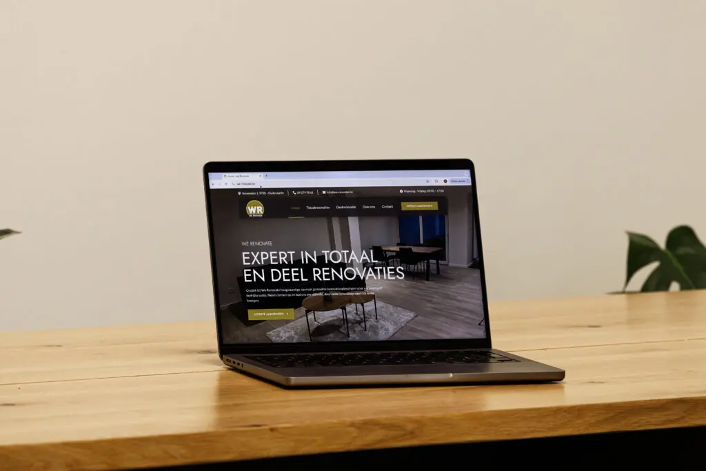 Laptop met de website van We Renovate op een houten bureau